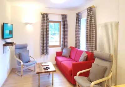 a living room with a red couch and two chairs at Casa Alfredino in Rocca Pietore