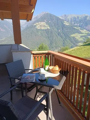 a table on a balcony with a bottle of wine at Prünsterhof Schenna in Schenna
