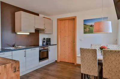 a kitchen with white cabinets and a table with chairs at Prünsterhof Schenna in Schenna