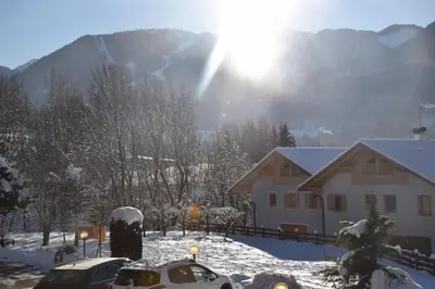 a snow covered yard with cars parked in front of a house at Casa Franca in Cavalese