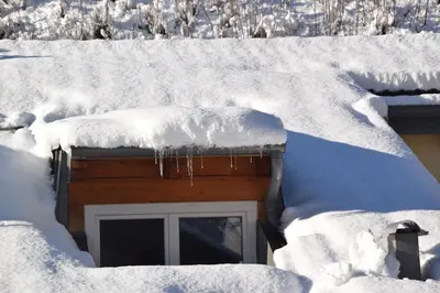 a snow covered roof of a house with a window at Casa Franca in Cavalese