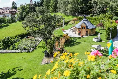 a garden with a small cabin in the grass at Alps Residence in Nova Ponente