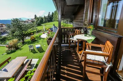 a balcony with chairs and a table and a view of a yard at Alps Residence in Nova Ponente