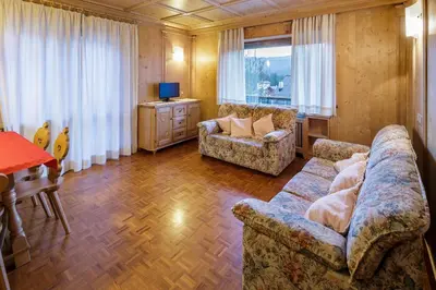 a living room with a couch and a table and a television at Villa Chiappuzza - Stayincortina in San Vito di Cadore