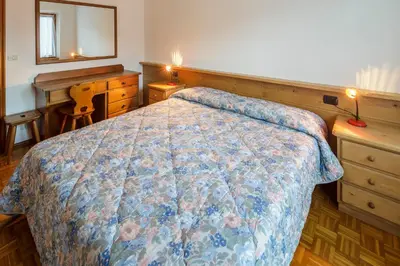 a bedroom with a bed and a desk and a mirror at Villa Chiappuzza - Stayincortina in San Vito di Cadore