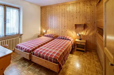 a bedroom with a bed in a room with wooden walls at Villa Chiappuzza - Stayincortina in San Vito di Cadore