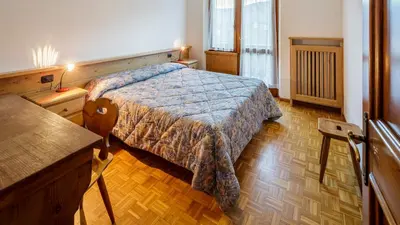a bedroom with a bed and a wooden floor at Villa Chiappuzza - Stayincortina in San Vito di Cadore