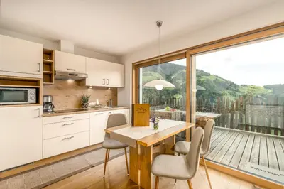 a kitchen with a table and chairs and a large window at Tratterhof Apartments in Vallarga