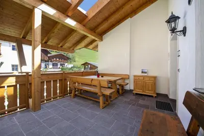 a porch with a wooden table and a bench at Schoenau Bio & SPA Family Apartments in San Pietro in Gardena