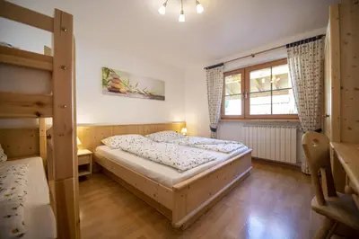 a bedroom with a bed and a window at Schoenau Bio & SPA Family Apartments in San Pietro in Gardena