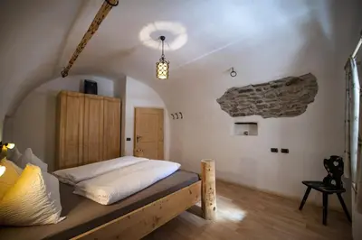 a bedroom with a bed in a room with a stone wall at Schoenau Bio & SPA Family Apartments in San Pietro in Gardena