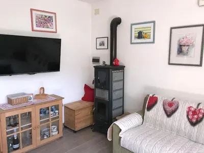 a living room with a flat screen tv and a wood stove at Almida in Castello di Fiemme
