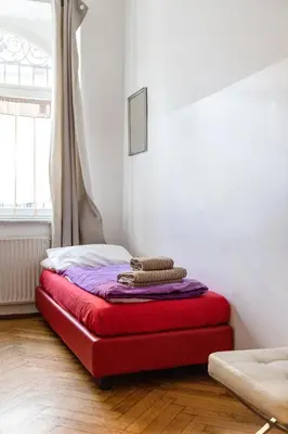 a red bed in a room with a window at Bolzano Rooms in Bolzano