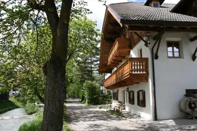 a building with wooden balconies next to a tree at Apperlehof in Villabassa