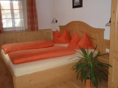 a bedroom with a wooden bed with orange pillows at Apperlehof in Villabassa