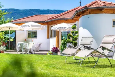 a house with lawn chairs and tables and umbrellas at Haus Oberhofer in Cornaiano