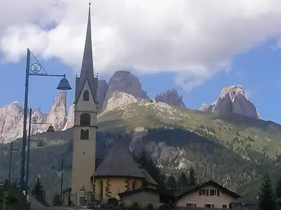 a church in front of a mountain with a street light at Albergo Arnica in Canazei