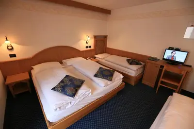 a hotel room with two beds and a flat screen tv at Albergo Arnica in Canazei
