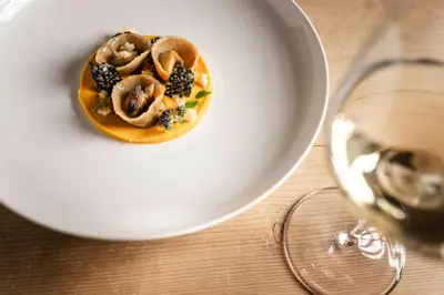 a plate of food on a table next to a wine glass at Hotel Steger-Dellai in Alpe di Siusi
