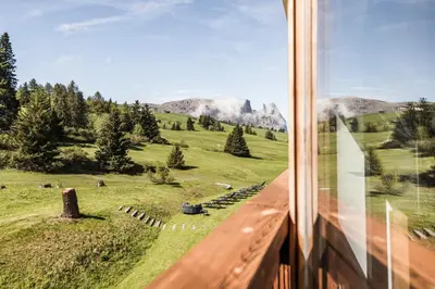 a view from a train window of a field and mountains at Hotel Steger-Dellai in Alpe di Siusi