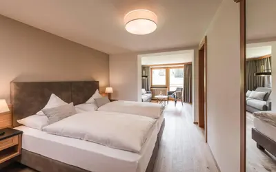 a bedroom with a large bed and a living room at Hotel Steger-Dellai in Alpe di Siusi