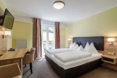 a hotel room with a bed and a desk and a television at Hotel Mitlechnerhof in Schenna