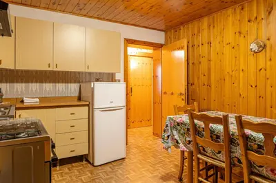 a kitchen with a table and a white refrigerator at Cèsa Silvano in Rocca Pietore