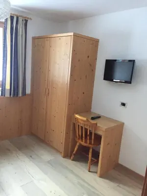 a room with a desk and a cabinet and a television at Pederü in San Vigilio Di Marebbe