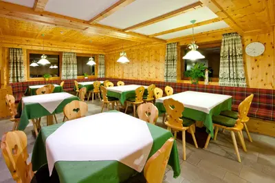 a restaurant with green and white tables and chairs at Pederü in San Vigilio Di Marebbe