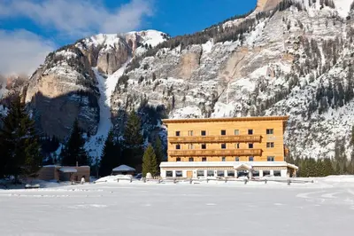 a large building in front of a mountain at Pederü in San Vigilio Di Marebbe