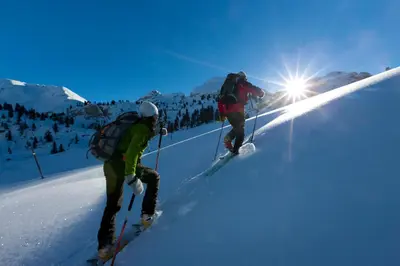 two people are skiing down a snow covered slope at Pederü in San Vigilio Di Marebbe
