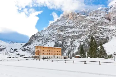 a building in the snow in front of a mountain at Pederü in San Vigilio Di Marebbe