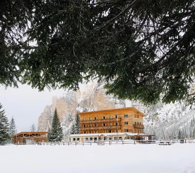 a large building in the snow in front of a mountain at Pederü in San Vigilio Di Marebbe