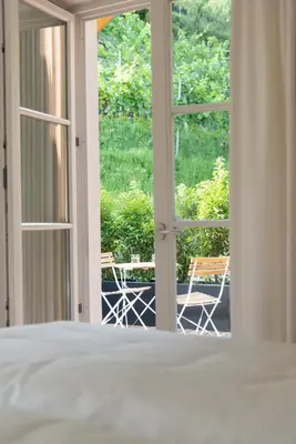 a bedroom with a bed and a window with chairs at Huberhof Meran in Merano