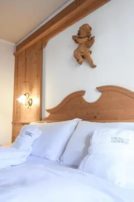 a teddy bear sitting on the top of a bed at Hotel Relais Grünwald in Cavalese