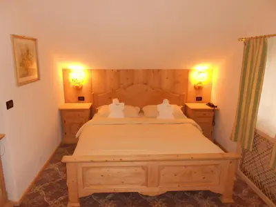 a bedroom with a large bed with two night stands at Hotel Relais Grünwald in Cavalese