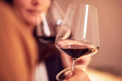 a woman is holding a glass of red wine at Hotel Enzian in Villa Ottone