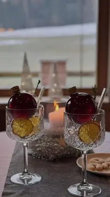 two glasses with fruit in them on a table with a candle at Hotel Enzian in Villa Ottone