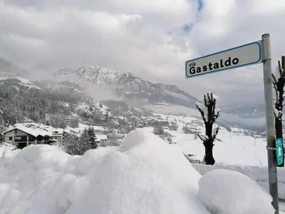 a street sign in the snow next to a mountain at Appartamento Bellavista in Cavalese