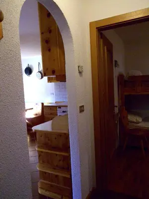 a kitchen with an archway leading into a kitchen with a table at Appartamento Bellavista in Cavalese