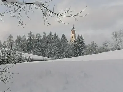 a building with a clock tower in the snow at Appartamento Bellavista in Cavalese