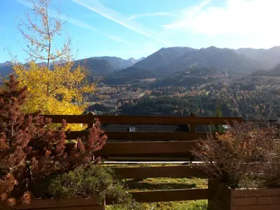 a wooden bench with mountains in the background at Appartamento Bellavista in Cavalese