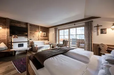 a bedroom with a large bed and a living room at Charmehotel Uhrerhof - Deur in Ortisei