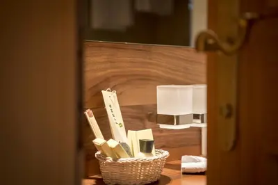 a basket of toothbrushes on a table next to a lamp at Charmehotel Uhrerhof - Deur in Ortisei