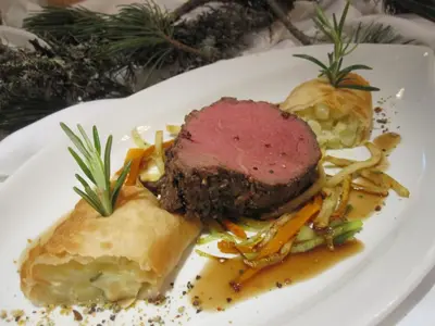 a plate of food with a piece of meat and vegetables at Naturhotel Sonnenhof in Chiusa