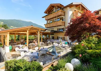 a restaurant with tables and chairs in front of a building at Naturhotel Sonnenhof in Chiusa