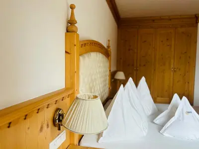 a bedroom with a bed with white pillows and a lamp at Naturhotel Sonnenhof in Chiusa