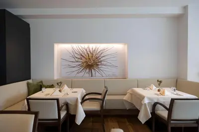 a dining room with two tables and a picture on the wall at Artnatur Dolomites Hotel & Spa in Siusi