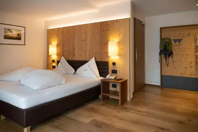 a bedroom with a bed with a wooden wall at Artnatur Dolomites Hotel & Spa in Siusi