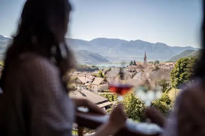 a woman sitting at a table with a glass of wine at Hotel Torgglhof in Caldaro